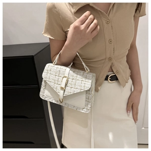 Detail of elegant cream tweed crossbody bag with gold metal buckle and leather trim