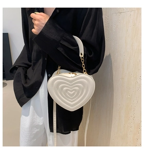 Weiße herzförmige Handtasche mit Steppmuster und Kettenriemen am Model gezeigt