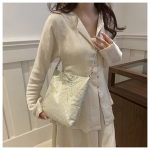 Detail of silk texture fabric with bamboo and kingfisher embroidery on crossbody bag