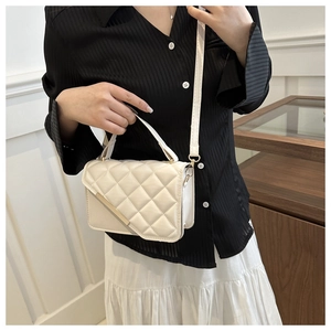 Detail showing the creamy white quilted texture and golden hardware of the stylish handbag