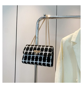 Detail of tweed checkered chain bag hanging with a cream blazer in a lifestyle setting