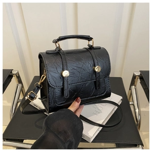 Détail du sac à main en cuir plissé noir avec boucles dorées et poignée solide