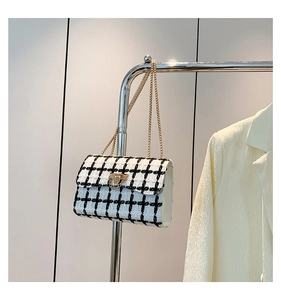 Detail of classic black and white tweed crossbody bag with gold chain and twist-lock