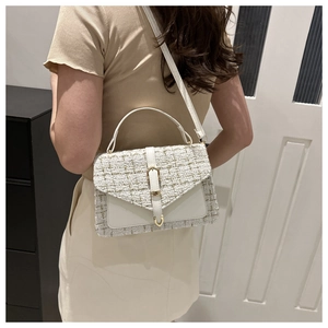 Détail du sac à main en tweed blanc avec fermoir doré porté par le mannequin
