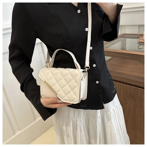 Close-up of white quilted crossbody bag featuring elegant gold metal trim and strap