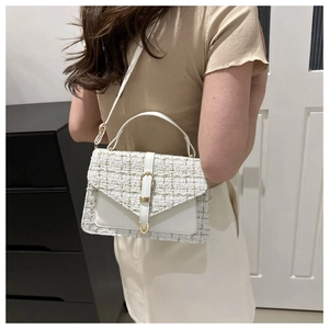 Sac à bandoulière en tweed blanc sur mannequin avec boucles dorées et rabat