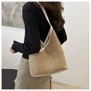 Detail of hand-woven straw shoulder bag with creamy white leather trim on a female model