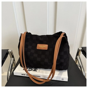 Detail of black woven texture tote bag with brown straps on a white book display