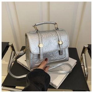 Détail du sac à main argenté métallisé avec boucle dorée sur une chaise noire vintage