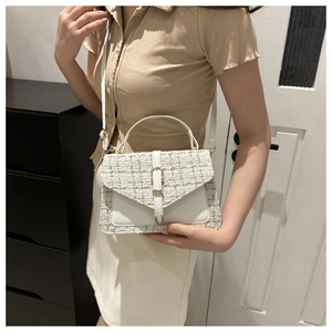 Détail du sac bandoulière en tweed avec boucle dorée porté par un mannequin en salle