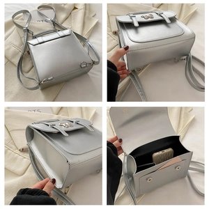 Detail view of silver crossbody bag featuring metal butterfly clasp and inner compartments