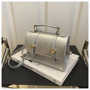Vue détaillée du sac argenté avec texture plissée unique et boucles métalliques dorées
