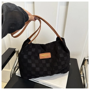 Close-up of black and white checkerboard tote bag with brown leather handles and logo