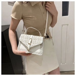 Sac à main élégant en tweed blanc avec tissage doré et poignée en cuir porté par un mannequin