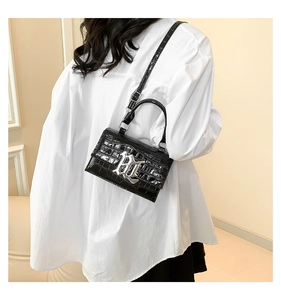 Detail of glossy black stone-patterned handbag with silver metal gothic lettering