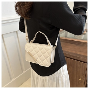 Detail of white quilted crossbody bag with gold metal trim and adjustable strap