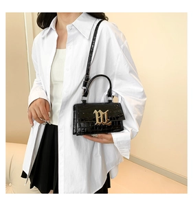Detailed close-up of black crocodile pattern leather texture and golden metal buckle