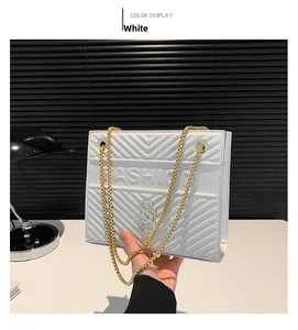 Detail of white quilted handbag with golden S-buckle and FASHION lettering text