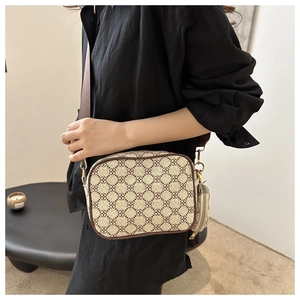 Detail of camera bag with geometric print, wide strap and small round coin purse charm