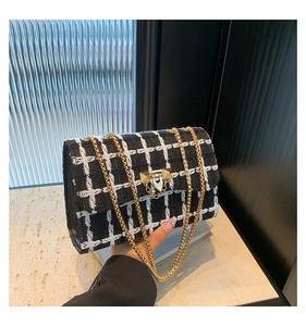 Detailed shot of black and white tweed pattern bag with gold chain and studded clasp