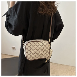 Model wearing a retro floral crossbody bag with a wide strap and small round charm