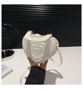 Nahaufnahme der weißen herzförmigen Ledertasche mit Steppung und goldener Kette