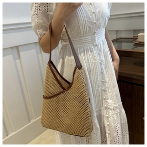 Detail of hand-woven straw bucket bag with brown leather trim and hollow geometric pattern