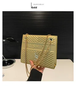 Detail of gold quilted shoulder bag with FASHION lettering and metallic chain strap
