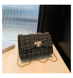 Detail of black tweed shoulder bag with golden chain and metallic geometric clasp