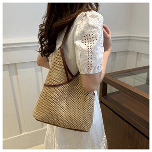 Close-up of straw woven bucket bag with brown leather trim on a white lace dress
