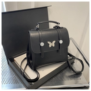 Detail of black matte PU leather backpack with silver butterfly accent in a gift box