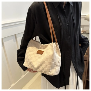 Detail of cream woven tote bag with brown leather straps and fashion label tag