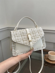 Sac à bandoulière chic en cuir crème et tweed avec boucle dorée dans un décor de café