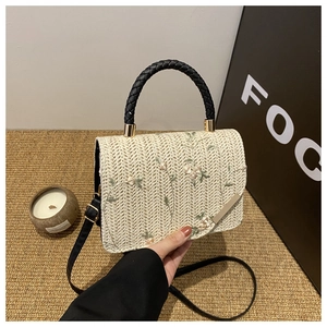 Close-up of elegant floral embroidery and woven texture on a straw crossbody bag