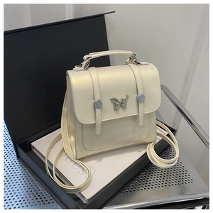 Detail of cream white backpack featuring silver butterfly buckle and gift packaging