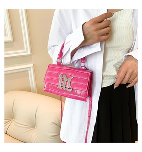 Detail of rose pink crocodile pattern handbag with large silver gothic M metal buckle