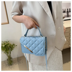 Macro detail of quilted rhombus pattern on light blue leather bag with gold metal trim