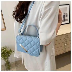 Light blue quilted leather crossbody bag styled with a white blazer in a home setting