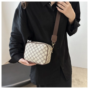 Detail of crossbody bag with vintage brown clover pattern and wide woven strap