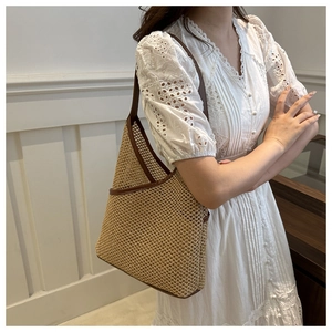 Detail of hand-woven bucket bag with brown leather shoulder strap and hollow texture