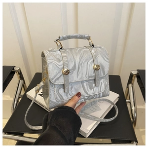 Détail du sac à motif marbre argenté avec d'élégantes ferrures cylindriques dorées