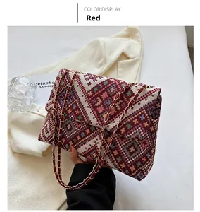 Detail of red geometric pattern woven bag with metal chain strap and woven texture