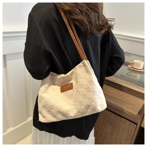 Close-up of a cream-white tote bag with woven texture and brown leather branding