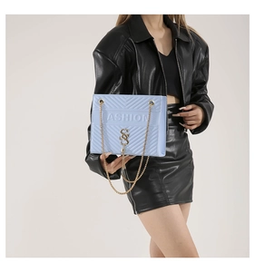 Detail of light blue quilted chain shoulder bag with gold logo and tassel accent