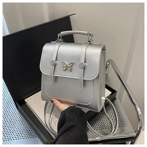 Close-up of silver mini backpack featuring a metallic butterfly clasp and fine stitching