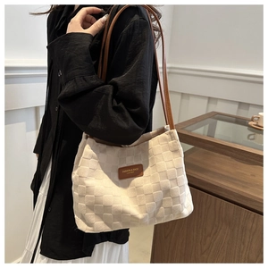 Detail of off-white woven tote bag with brown leather straps and fashion label tag