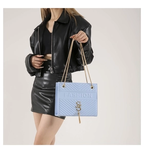 Detail view of light blue crossbody bag with V-quilted pattern and gold chain strap