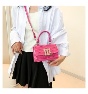 Close-up of pink faux leather bag with crocodile pattern and golden M hardware