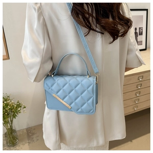 Light blue quilted leather crossbody bag with gold trim worn by a model in casual setting