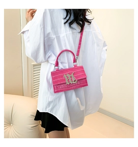 Detail of bright pink crocodile embossed mini bag with silver M logo and chain strap